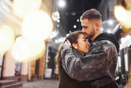 Embracing each other. Happy multiracial couple together outdoors in the city celebrating New year.