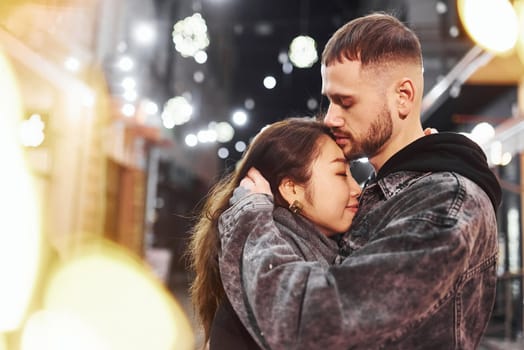 Embracing each other. Happy multiracial couple together outdoors in the city celebrating New year.
