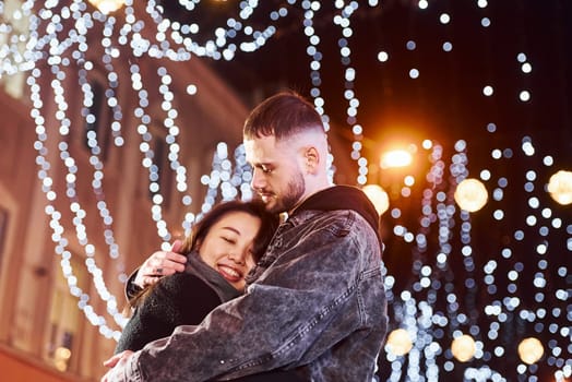 Embracing each other. Happy multiracial couple together outdoors in the city celebrating New year.