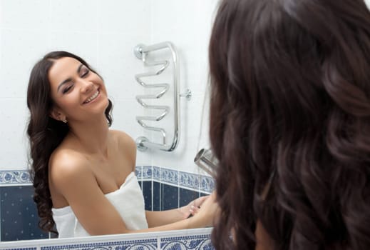 Happy pretty woman with hairdryer in bathroom