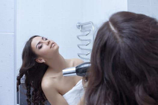 Young brunette woman with hairdryer in bathroom
