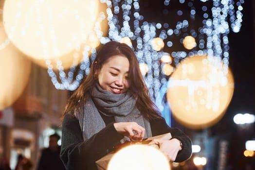 With gift box. Cute and happy asian young woman outdoors in the city celebrates New year.