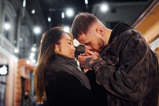 Embracing each other. Happy multiracial couple together outdoors in the city celebrating New year.