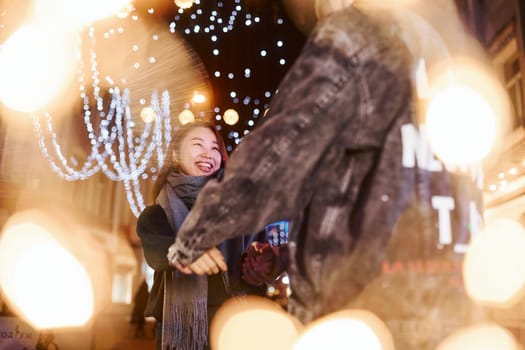 Artificial lighting by garlands. Happy multiracial couple together outdoors in the city celebrating New year.