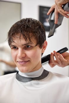 Professional hairdresser using hair dryer and comb in barber shop. Haircut in the barbershop.