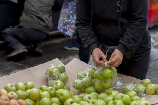 saleswoman putting green apples in a plastic bag. High quality photo