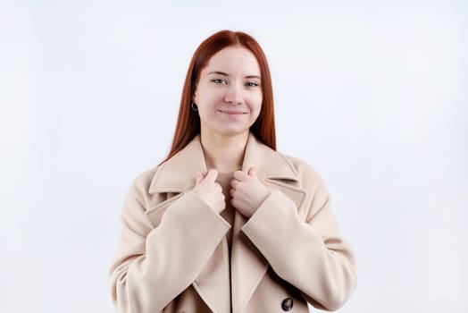 beautiful young woman in beige coat choosing outfit dressing on white background. Selection of a wardrobe, stylist, shopping.