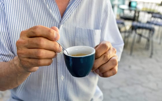 Lifestyle concept. An elderly man drinking espresso coffee at an outdoor cafe in the early hours of the morning before work.
