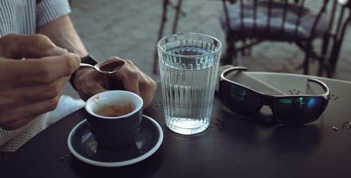 Lifestyle concept. An elderly man drinking espresso coffee at an outdoor cafe in the early hours of the morning before work.
