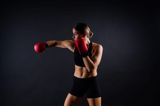 Strong sportswoman in boxing gloves prepared high kick. Isolated on a white, red, yellow background