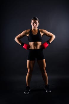 Strong sportswoman in boxing gloves prepared high kick. Isolated on a white, red, yellow background