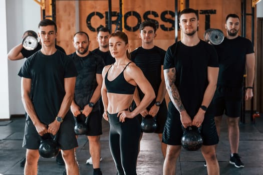 Posing for a camera. Group of young sportive people have crossfit day indoors in gym.
