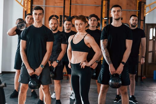 Posing for a camera. Group of young sportive people have crossfit day indoors in gym.