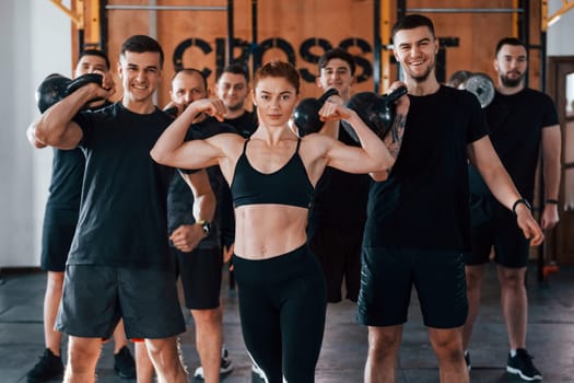 Posing for a camera. Group of young sportive people have crossfit day indoors in gym.