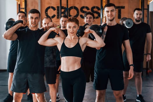 Posing for a camera. Group of young sportive people have crossfit day indoors in gym.