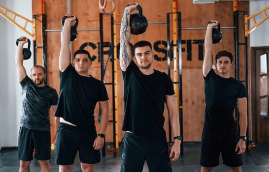 Lifting of heavy weights. Group of young sportive people have crossfit day indoors in gym.