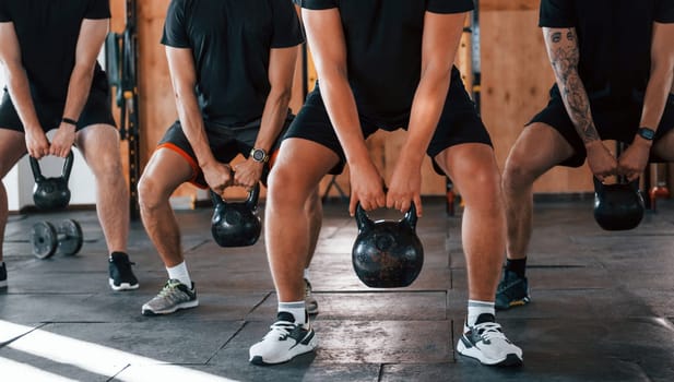 Lifting of heavy weights. Group of young sportive people have crossfit day indoors in gym.