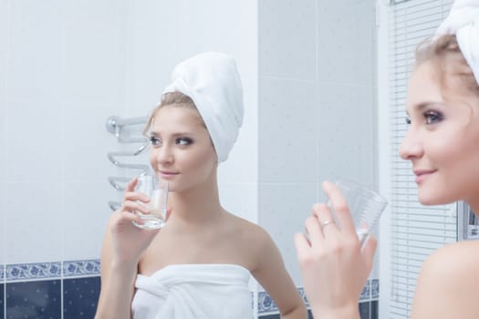 Portrait of woman with glass in bathroom