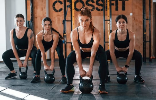 Lifting of heavy weights. Group of young sportive people have crossfit day indoors in gym.