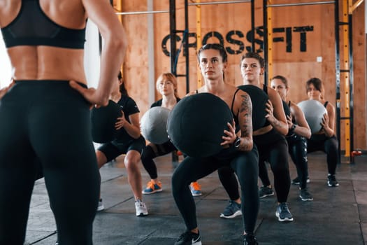 With fitness balls. Group of young sportive people have crossfit day indoors in gym.