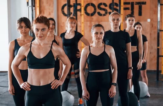 Posing for a camera. Group of young sportive people have crossfit day indoors in gym.