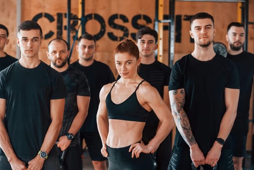 Posing for a camera. Group of young sportive people have crossfit day indoors in gym.