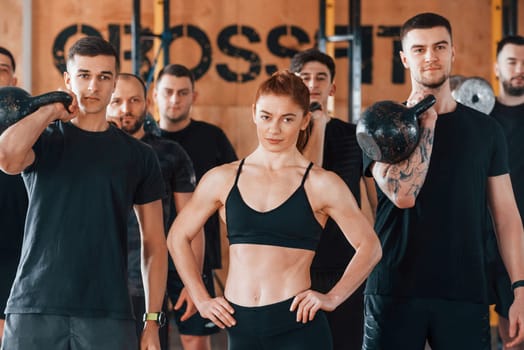 Posing for a camera. Group of young sportive people have crossfit day indoors in gym.