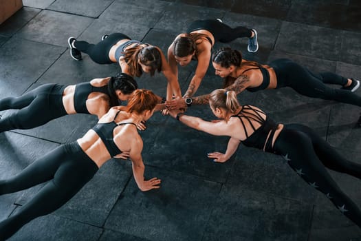 Plank exercise. Group of young sportive people have crossfit day indoors in gym.