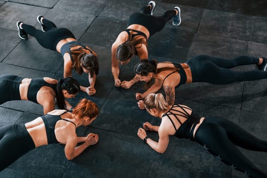 Plank exercise. Group of young sportive people have crossfit day indoors in gym.