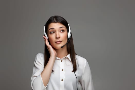 attentive beautiful woman with headphones and microphone is listening attentively to clints. Call center