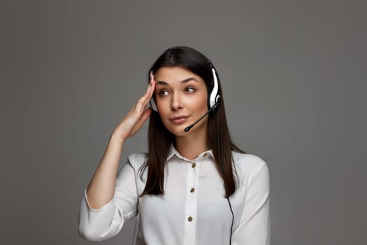 female call center agent looking tired and bored on gray background. Call center, business people concept