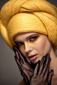 Beauty blonde model girl with fashionable creative make-up, bright eye line wear yellow turban in lace gloves. Creative eye makeup ideas.