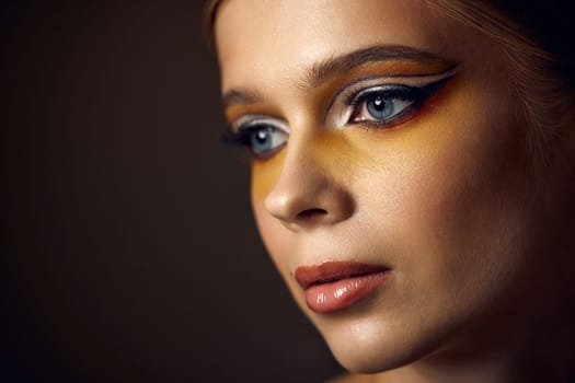 close-up portrait of beauty blonde model girl with fashionable creative make-up, bright eye line. Creative yellow eye makeup ideas.