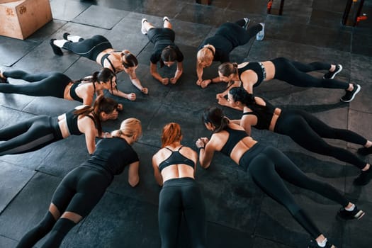 Busy by doing exercises. Group of young sportive people have crossfit day indoors in gym.