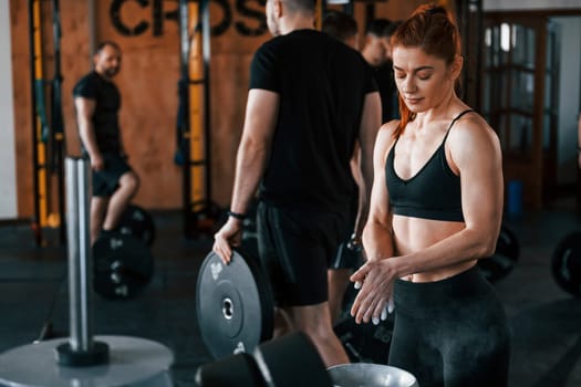 Group of young sportive people have crossfit day indoors in gym.
