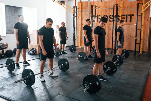 Group of young sportive people have crossfit day indoors in gym.