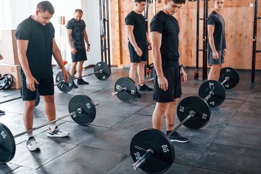 Group of young sportive people have crossfit day indoors in gym.