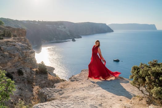 A woman in a red flying dress fluttering in the wind, against the backdrop of the sea