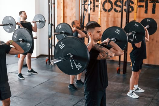 Group of young sportive people have crossfit day indoors in gym.