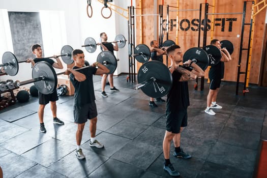 Group of young sportive people have crossfit day indoors in gym.