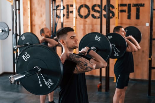 Group of young sportive people have crossfit day indoors in gym.