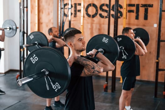 Group of young sportive people have crossfit day indoors in gym.