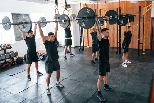 Group of young sportive people have crossfit day indoors in gym.