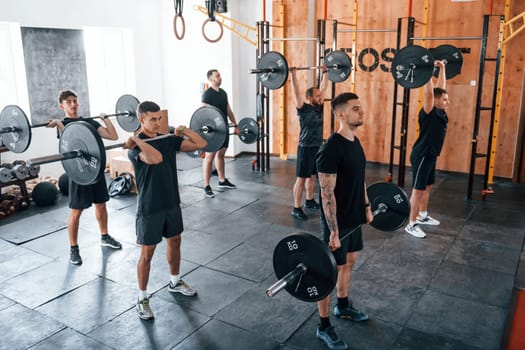 Group of young sportive people have crossfit day indoors in gym.