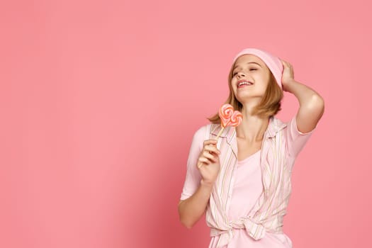 Lovely blonde woman holding candy on pink background. copy space