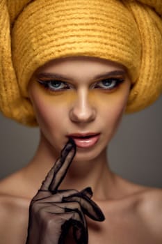 Beauty blonde model girl with fashionable creative make-up, bright eye line wear yellow turban. Creative eye makeup ideas.