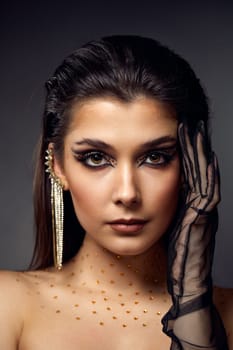 beauty fashionable model woman with creative eye makeup with arrows and rhinestones in long earring on gray background