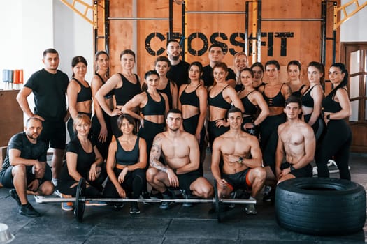 Group of young sportive people have crossfit day indoors in gym.