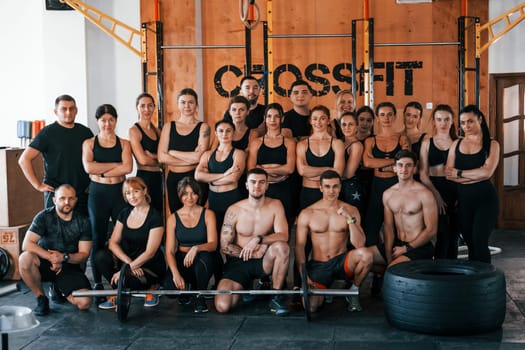 Group of young sportive people have crossfit day indoors in gym.