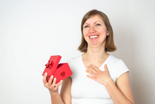Happy smiling women in white shirt with a red gift box on the white background. Happy valentines day.